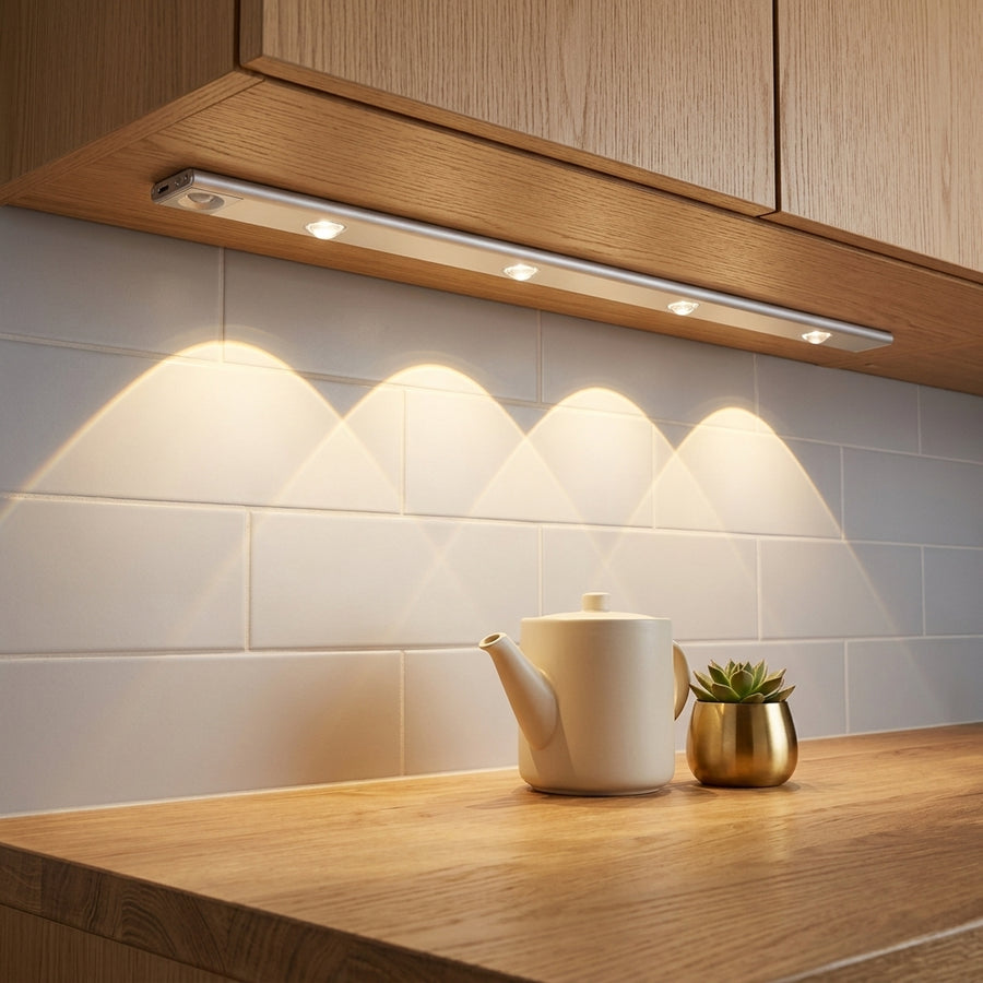 Barra LED instalada bajo un armario de cocina real, encendida iluminando la encimera