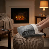 Persona usando el calentador de pies USB en un sillon junto a la chimenea