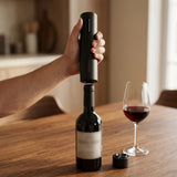 Persona usando el destapador sacacorchos eléctrico en una botella de vino