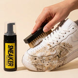 Mano cepillando zapatilla blanca sucia con el kit, mostrando limpieza en acción