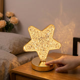 Mano encendiendo la lampara estrella de cristal en un velador