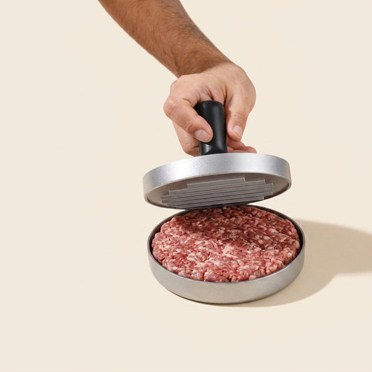 Mano presionando carne en el molde de hamburguesas